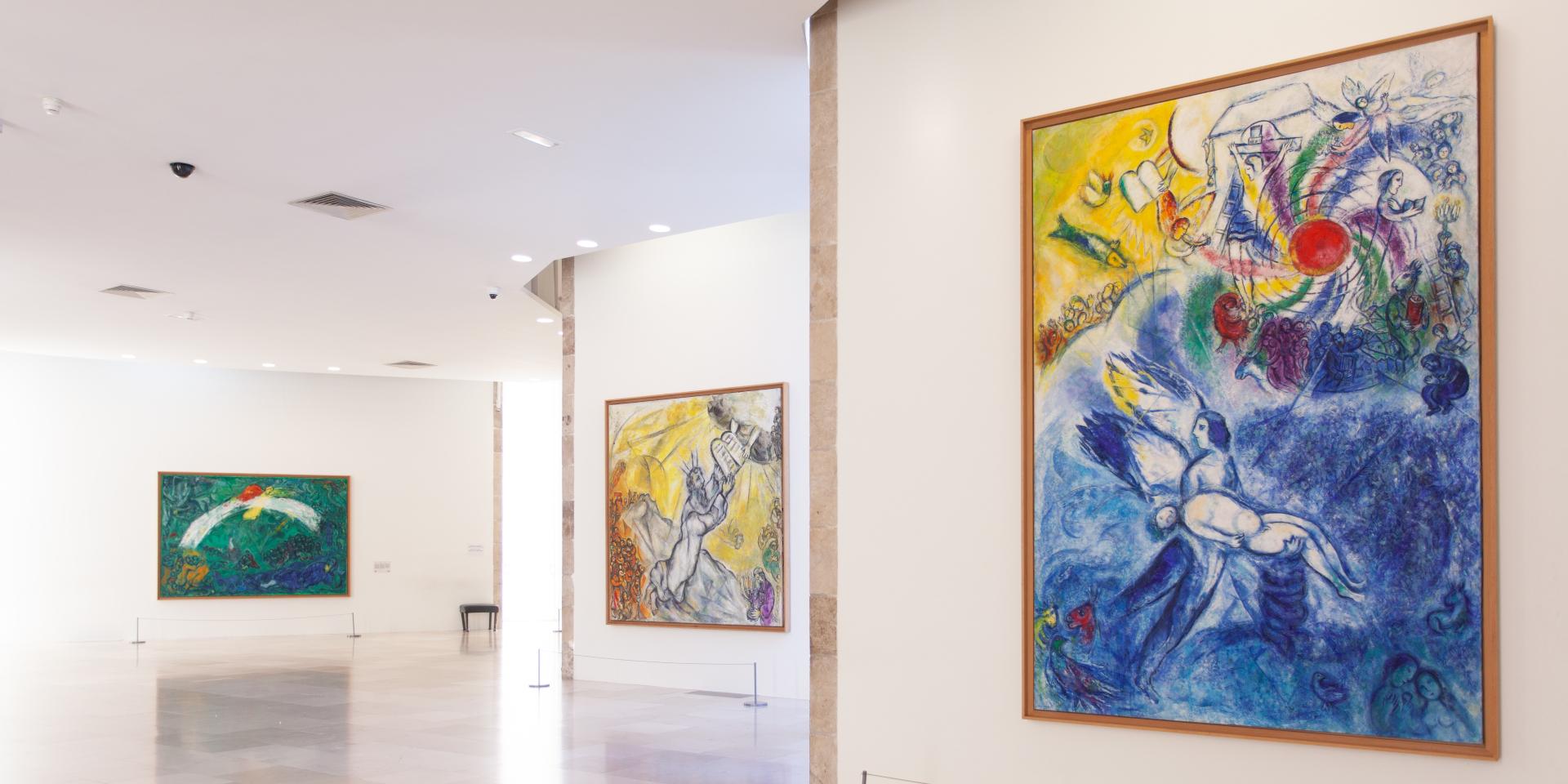vue de la salle du Message Biblique, avec les œuvres de Marc Chagall (de droite à gauche), La Création de l'Homme (1956-1958, huile sur toile), Moïse recevant les Tables de la Loi (1960-1966, hule sur toile), Noé et l'arc-en-ciel (1961-1966, huile sur toile). Photo : © musées nationaux du XXe siècle des Alpes-Maritimes © ADAGP, Paris, 2022.