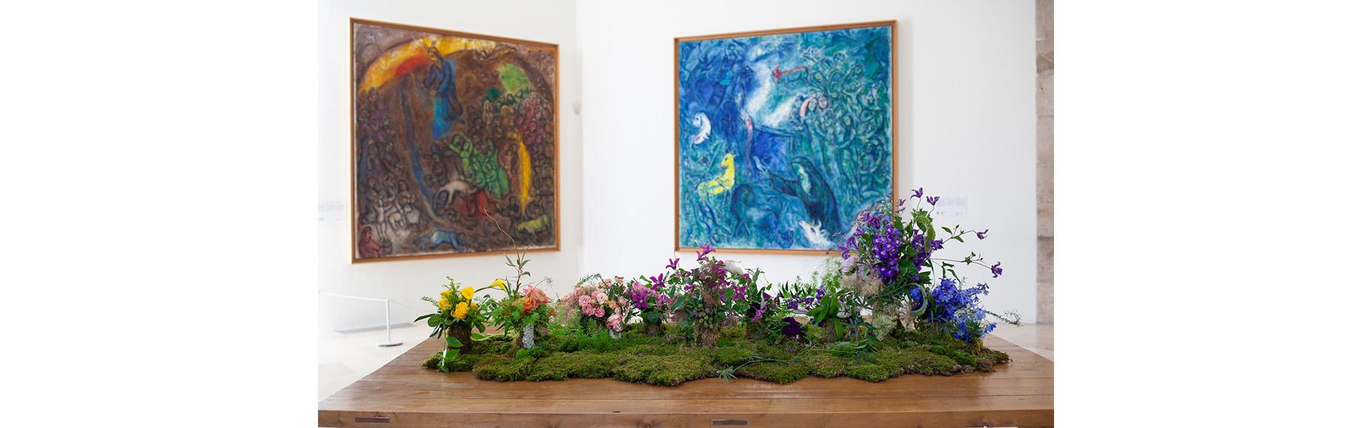 Composition florale de Bella Meyer, devant les œuvres de Marc Chagall, Le Frappement du rocher (1960-1966) et L'Arche de Noé (1961-1966). Nice, musée national Marc Chagall. Photo : (c) Gilles Ehrentrant (c) Adagp, Paris, 2024
